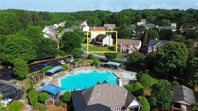 aerial perspective of suburban area with property parcel outlined, a pool, and a heavily wooded area