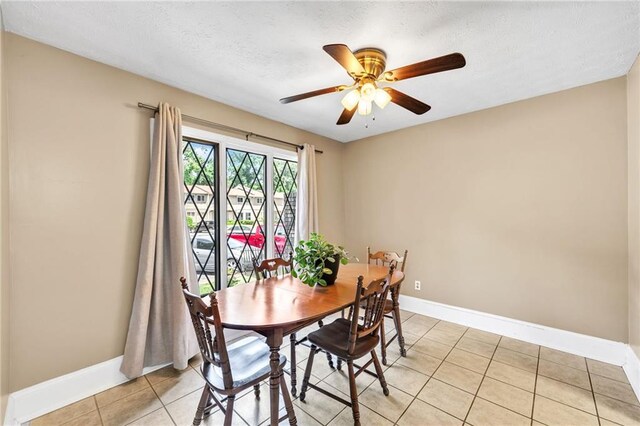 tiled dining room with ceiling fan and a textured ceiling