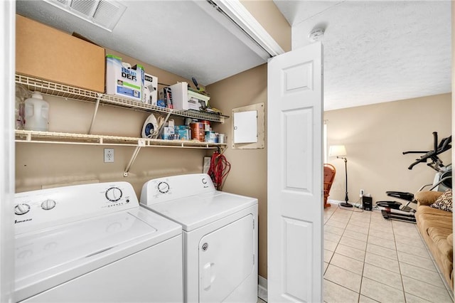 laundry area featuring light tile patterned floors, a textured ceiling, and washer and clothes dryer