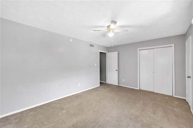 unfurnished bedroom featuring ceiling fan, a closet, carpet floors, and a textured ceiling