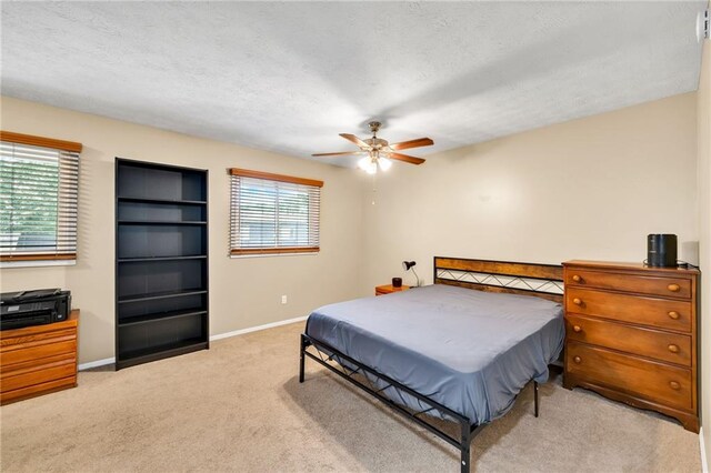 bedroom featuring a textured ceiling, ceiling fan, and light carpet