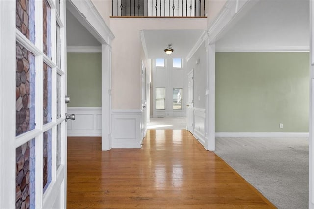 entrance foyer featuring ornamental molding, carpet floors, and a towering ceiling