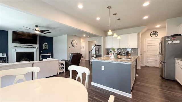 kitchen with freestanding refrigerator, a ceiling fan, open floor plan, white cabinets, and a sink