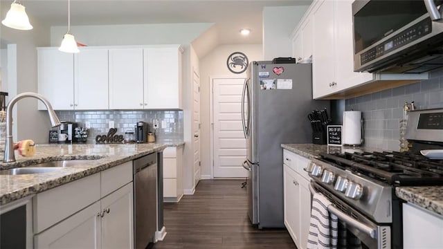 kitchen with appliances with stainless steel finishes, tasteful backsplash, a sink, white cabinetry, and dark wood-type flooring