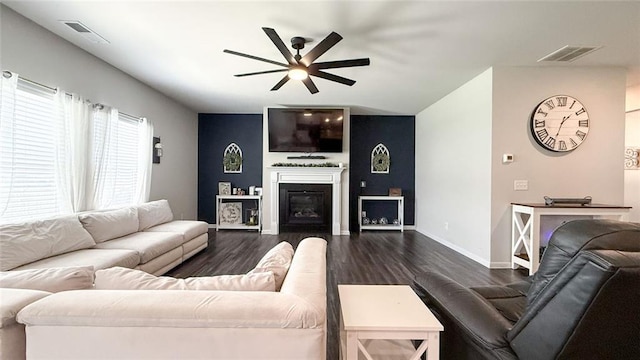 living area with dark wood-style flooring, ceiling fan, visible vents, and baseboards