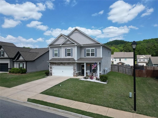 craftsman-style home with fence, an attached garage, a front lawn, covered porch, and driveway