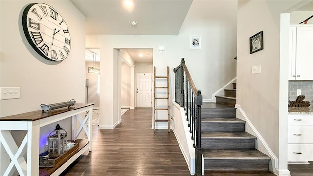 foyer entrance with baseboards, dark wood-style flooring, and stairs