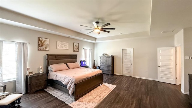 bedroom featuring baseboards, ceiling fan, a tray ceiling, and dark wood-style flooring