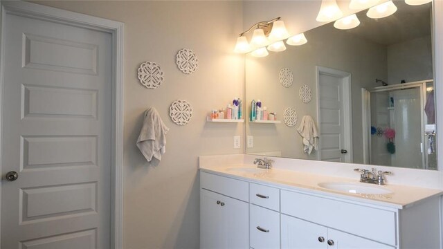 full bathroom featuring double vanity, a shower stall, and a sink