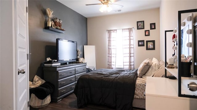 bedroom featuring ceiling fan, visible vents, and dark wood finished floors