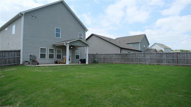 rear view of property featuring a lawn, a ceiling fan, a fenced backyard, and a patio area