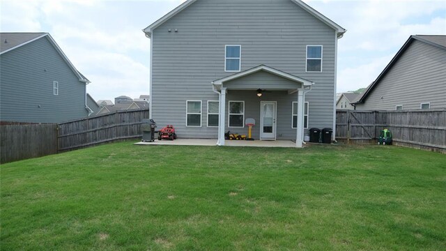 rear view of house with a lawn, a patio, ceiling fan, and a fenced backyard