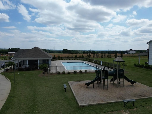 community playground with a community pool, a lawn, and fence