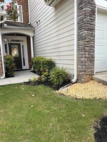 doorway to property featuring a garage and a lawn