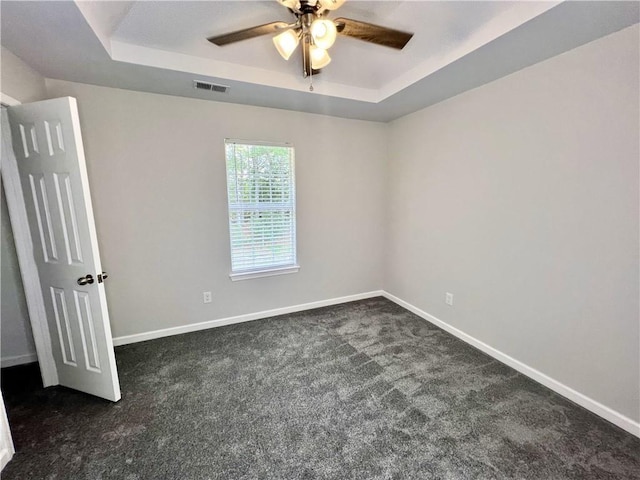 843 Kendall Park Dr, Winder, GA 30680 - empty room featuring a raised ceiling, dark colored carpet, and a ceiling fan