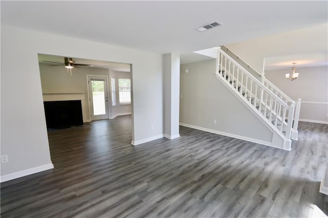 843 Kendall Park Dr, Winder, GA 30680 - unfurnished living room with stairs, dark wood-type flooring, a ceiling fan, a fireplace with flush hearth, and a chandelier