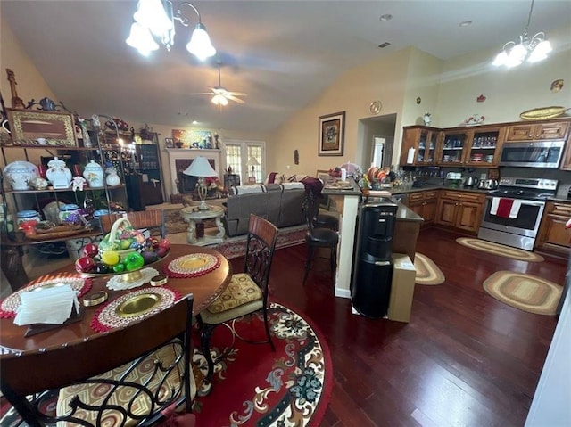 dining area with vaulted ceiling, dark wood finished floors, and ceiling fan with notable chandelier