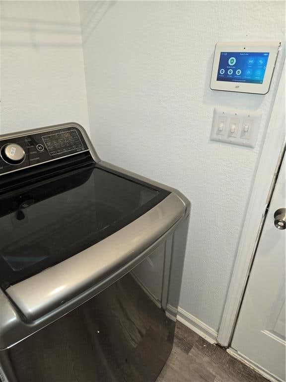 clothes washing area with dark hardwood / wood-style flooring and washer / clothes dryer