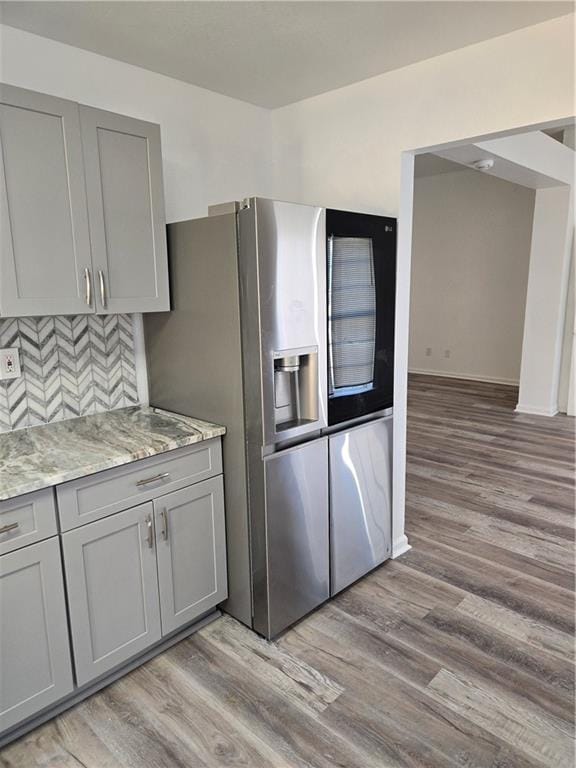 kitchen with stainless steel fridge with ice dispenser, backsplash, light hardwood / wood-style floors, and gray cabinetry