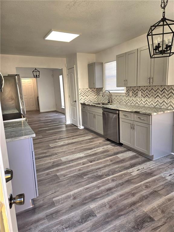 kitchen with dark hardwood / wood-style flooring, backsplash, dishwasher, gray cabinets, and hanging light fixtures