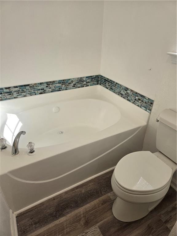 bathroom with a washtub, hardwood / wood-style floors, and toilet