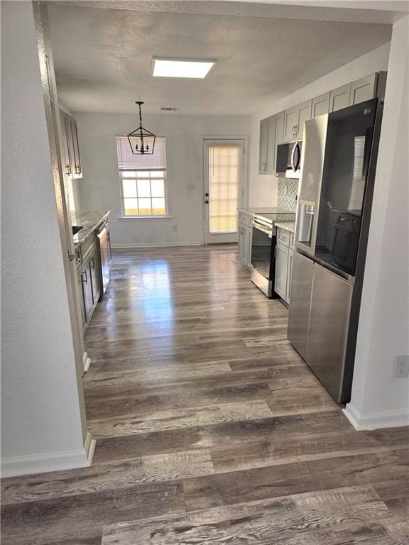 kitchen with decorative backsplash, stainless steel appliances, dark hardwood / wood-style floors, and a notable chandelier