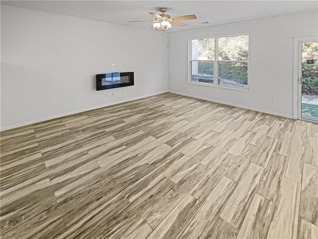 unfurnished living room featuring ceiling fan, light wood-type flooring, and a healthy amount of sunlight