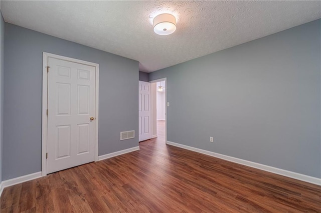 unfurnished bedroom with baseboards, wood finished floors, and a textured ceiling
