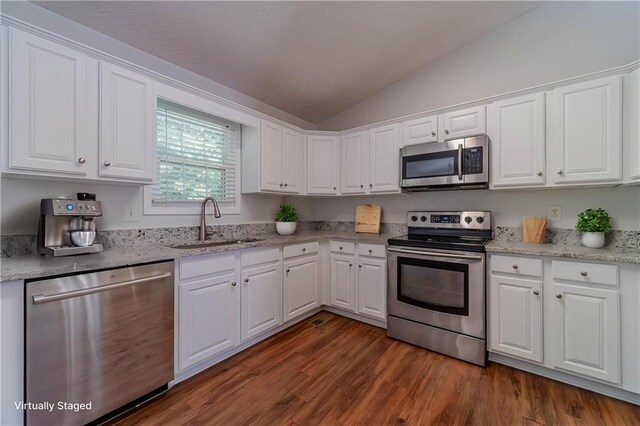 kitchen with appliances with stainless steel finishes, a sink, lofted ceiling, and white cabinets