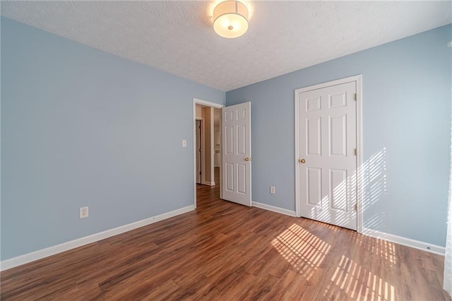 unfurnished bedroom featuring wood finished floors, baseboards, and a textured ceiling