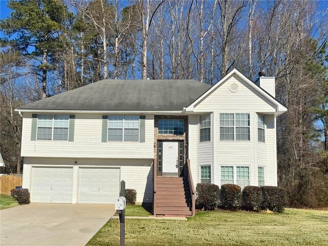 raised ranch featuring a garage and a front lawn