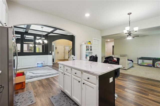 kitchen featuring arched walkways, open floor plan, freestanding refrigerator, and white cabinets