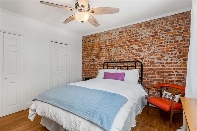 bedroom with brick wall, crown molding, wood finished floors, ceiling fan, and a closet