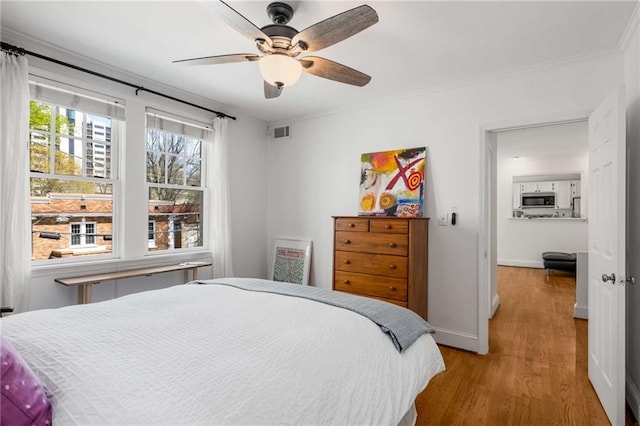 bedroom with wood finished floors, baseboards, ceiling fan, and ornamental molding