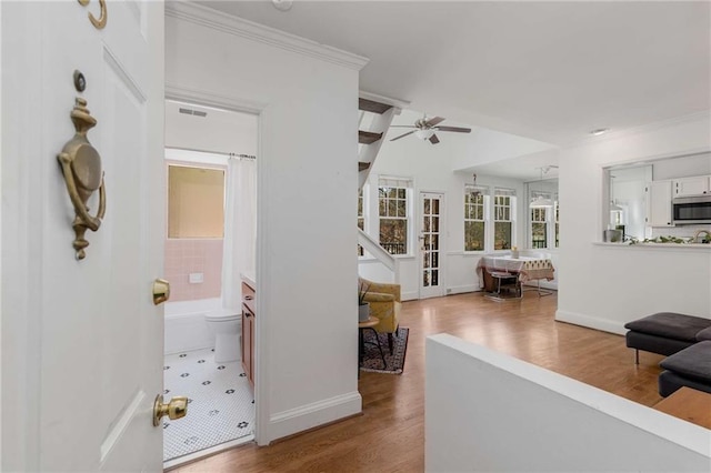 hall with wood finished floors, ornamental molding, and baseboards