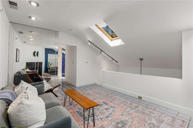 living area with lofted ceiling, a skylight, light tile patterned flooring, baseboards, and recessed lighting