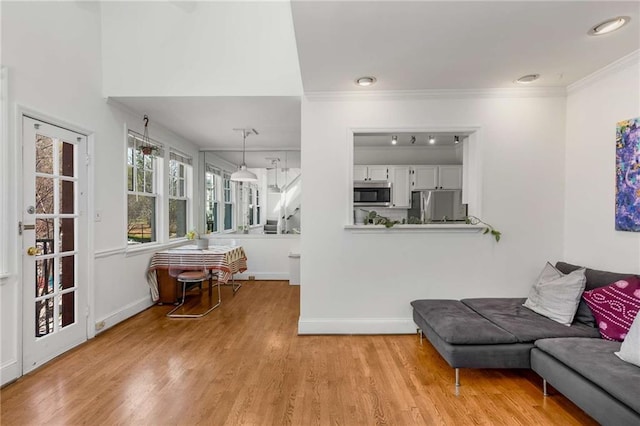 living room with crown molding, light wood-type flooring, and baseboards