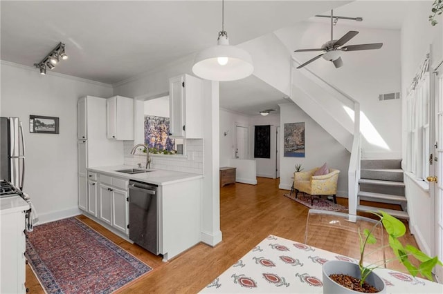 kitchen with a sink, stainless steel appliances, light countertops, a ceiling fan, and backsplash