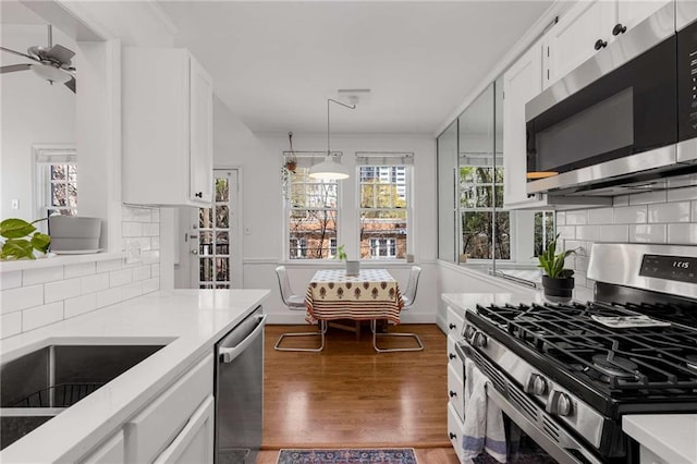 kitchen featuring stainless steel appliances, white cabinetry, light countertops, and wood finished floors