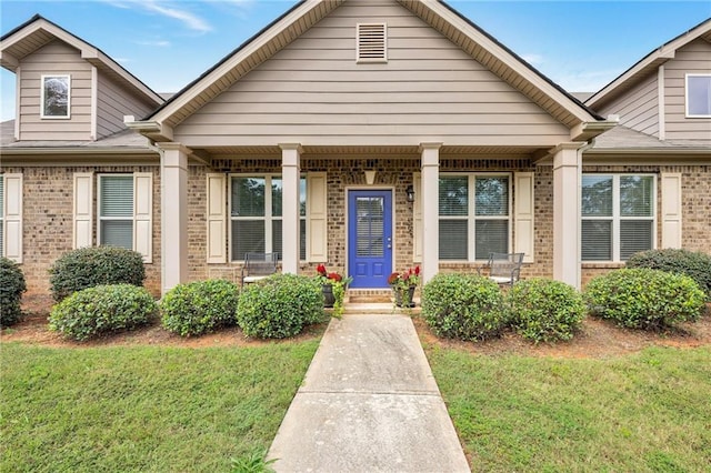 view of front of property featuring covered porch, a front lawn, and brick siding