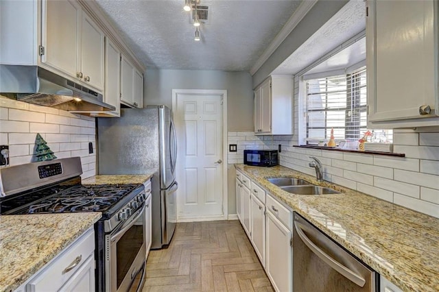 kitchen with stainless steel appliances, white cabinetry, sink, and light parquet floors