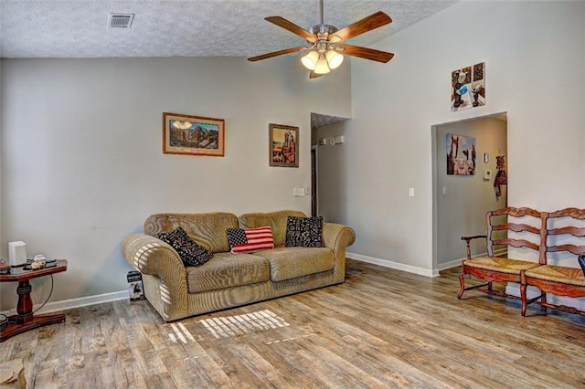 living room featuring ceiling fan, high vaulted ceiling, a textured ceiling, and light wood-type flooring