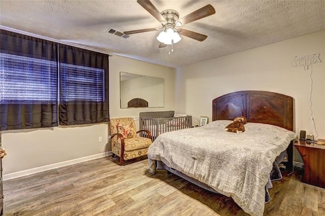 bedroom featuring ceiling fan, wood-type flooring, and a textured ceiling