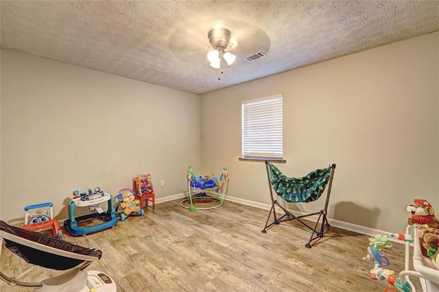 playroom featuring ceiling fan, hardwood / wood-style floors, and a textured ceiling