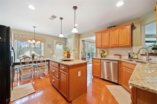 kitchen with sink, black refrigerator, a kitchen island, decorative light fixtures, and stainless steel dishwasher