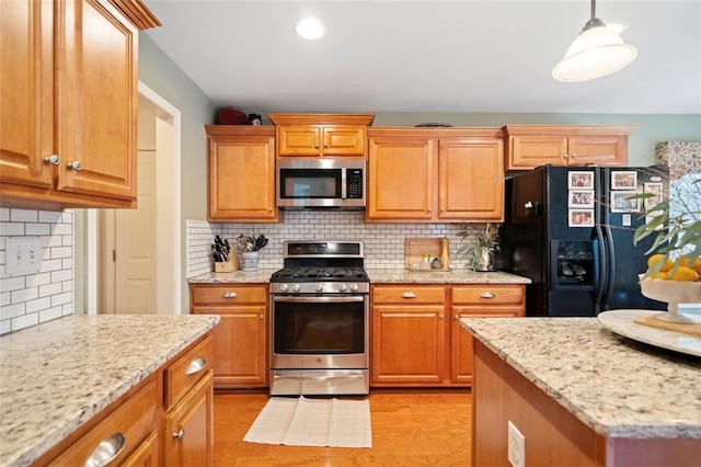 kitchen with light hardwood / wood-style flooring, pendant lighting, stainless steel appliances, light stone countertops, and backsplash