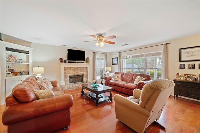 living room with ceiling fan, a fireplace, and light hardwood / wood-style flooring