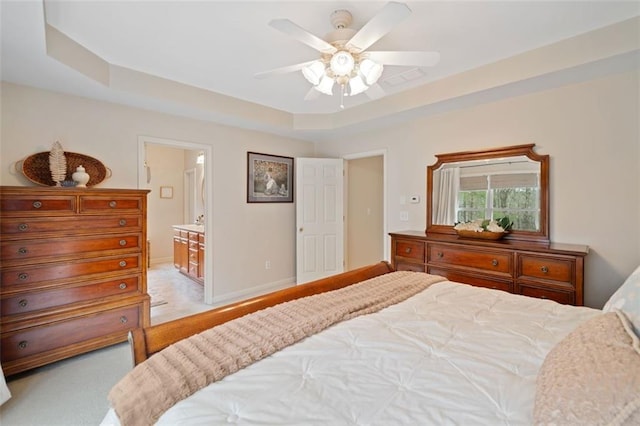 bedroom with connected bathroom, a tray ceiling, and ceiling fan