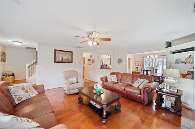 living room featuring wood-type flooring and ceiling fan with notable chandelier