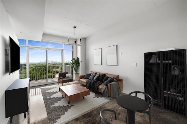 living room featuring finished concrete flooring, floor to ceiling windows, and a chandelier